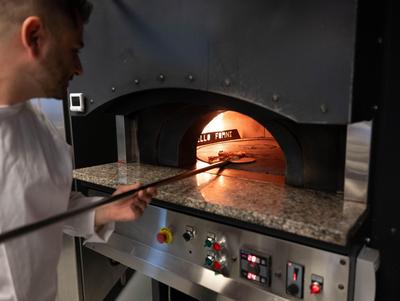 Cook takes a pizza out of the pizza oven