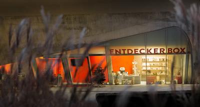 Illuminated shop window of the shop with "Entdeckerbox" lettering