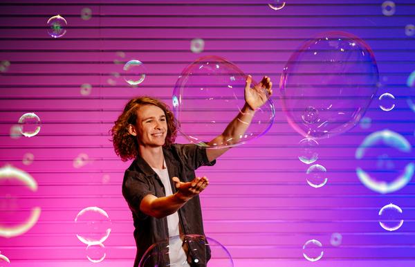 Young man blows huge soap bubbles